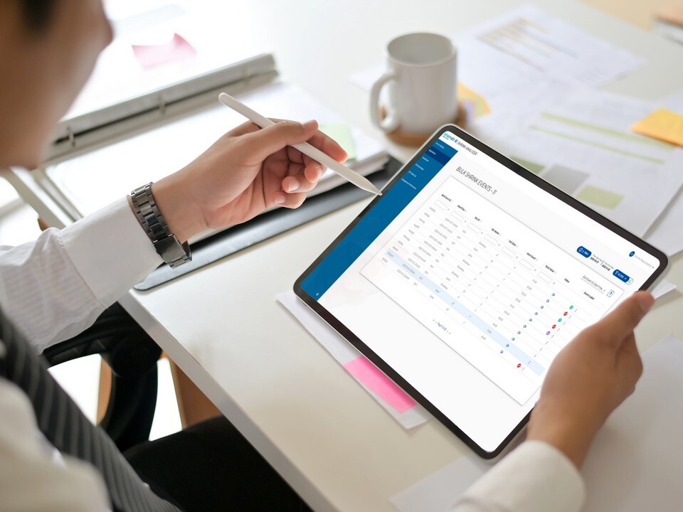 male retail store manager sitting at desk reviewing shrink analyzer report on a tablet device