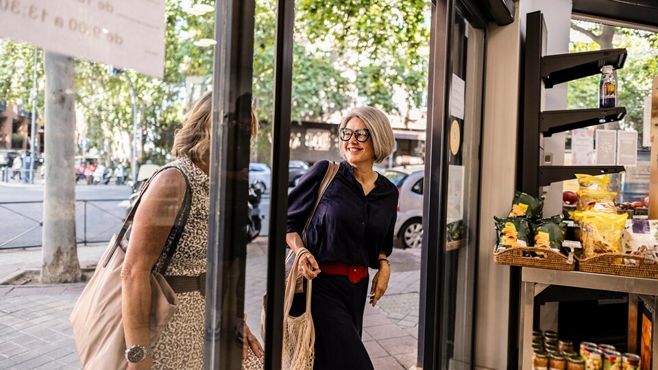 two middle aged women entering a bright modern retail grocery store