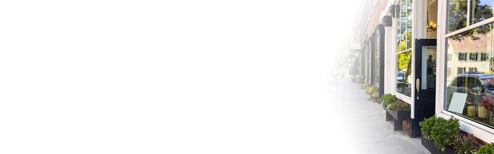 row of main street shopping district stores fading into white gradient background