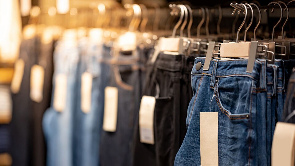wall racks of various colors of jeans with prominent tags in a bright retail apparel store