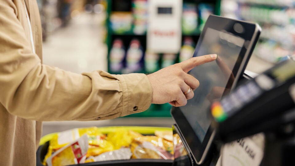 retail shopper touching a touchscreen display at a self-checkout kiosk in a retail store