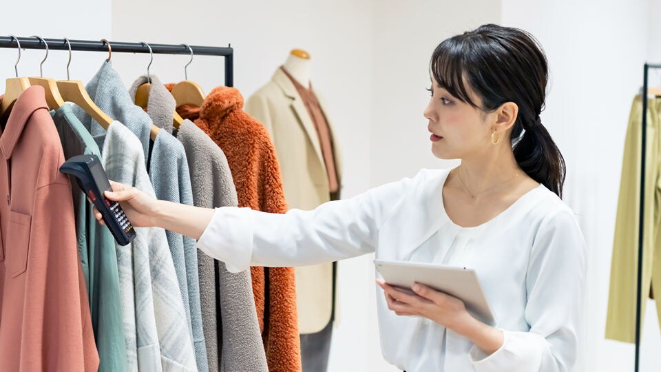 female store employee counting apparel inventory with electronic device