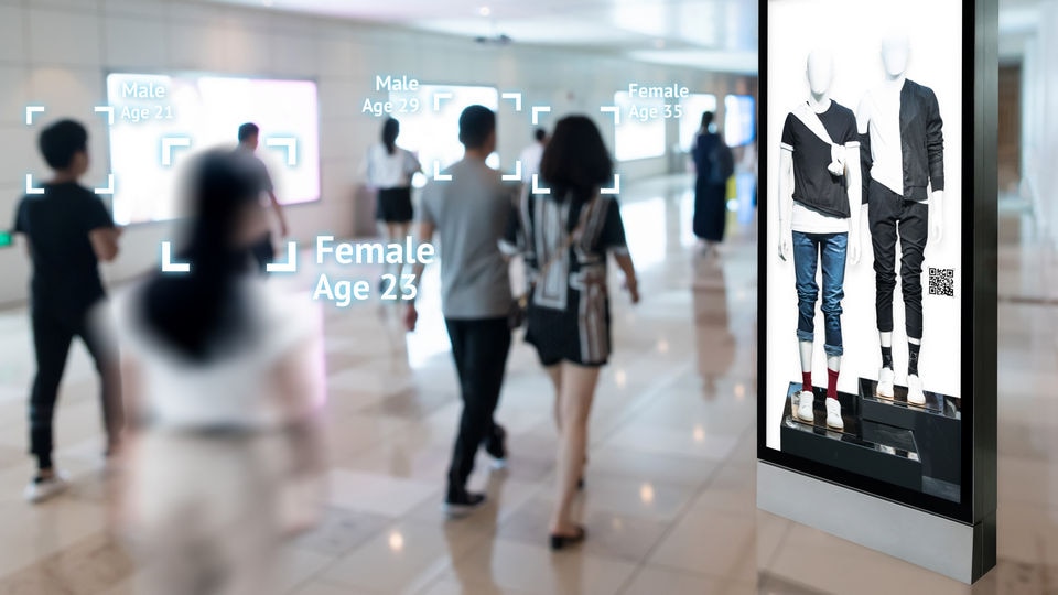 shoppers identified demographically by computer vision pass by a personalized advertising display in retail mall