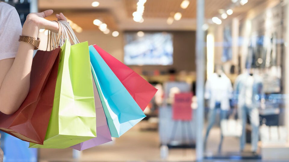 female shopper carrying multiple shopping bags inside retail mall