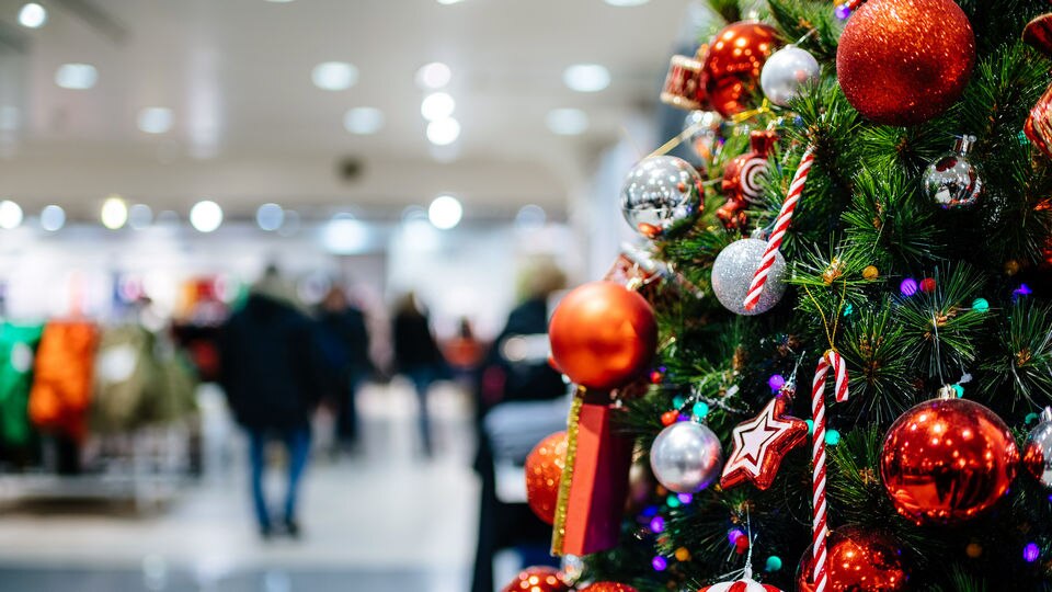 close-up of highly decorated christmas tree inside retail shopping mall with customers blurred in the background