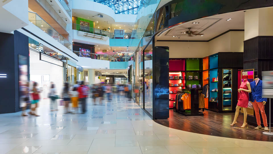 interior of multi-level retail shopping mall with customers and mannequins in the foreground