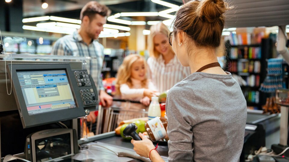 woman retail store associate scanning items at point of sale for family of man woman and child shoppers