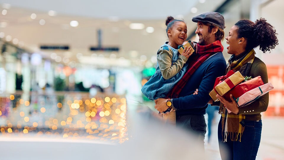 cheerful multiracial family of male and female and female child enjoying christmas holiday season retail shopping