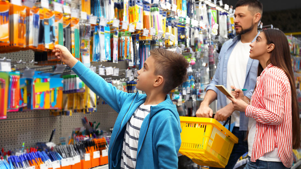 child and parents shopping for back to school supplies in retail stationery store