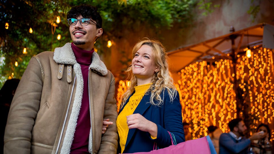male and female couple leaving a retail shopping area carrying shopping bags