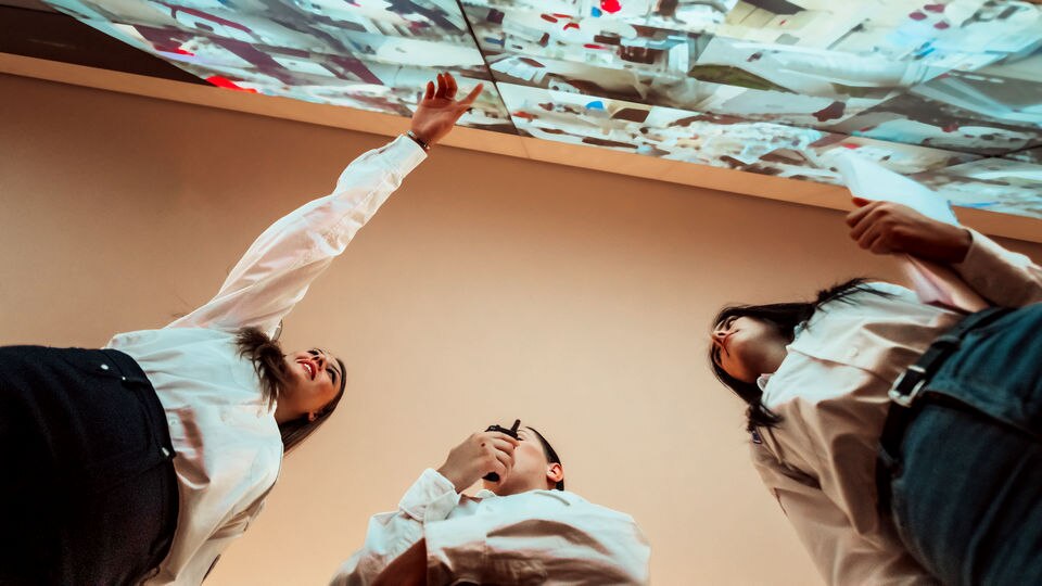 three retail security employees looking at video wall of store surveillance