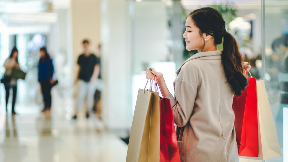 woman carrying shopping bags walking in retail shopping mall