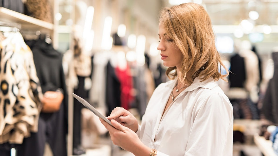 Woman in retail clothing store holding a tablet device