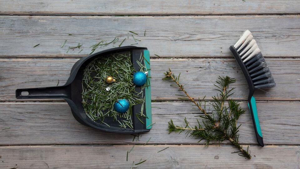 dustpan and handbroom with post-holiday season debris including tree branches and ornaments