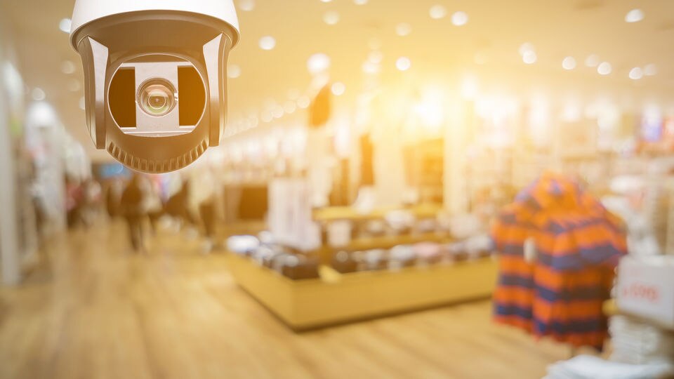 video surveillance camera on ceiling of retail clothing store with gold colored filter over image