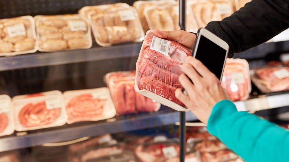 grocery retail customer holding package of meat and scanning label with smartphone barcode app