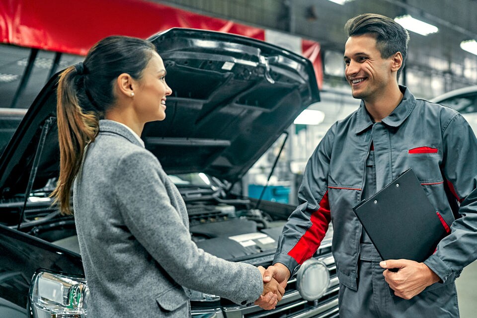 retail customer and mechanic shaking hands in the work floor of an automobile maintenance and repair shop