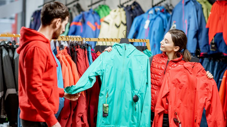 male and female shoppers looking at outerwear in retail sporting goods store