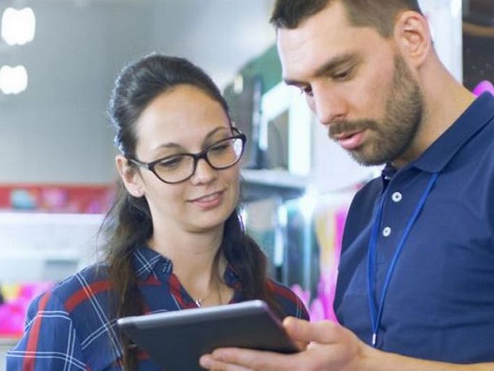 two retail store associates viewing a device on the sales floor