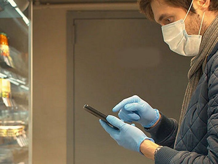 man in mask and gloves interacting with device in retail store