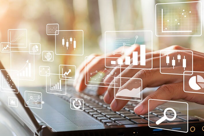 conceptual image of hands on laptop keyboard with floating icons and graphs above