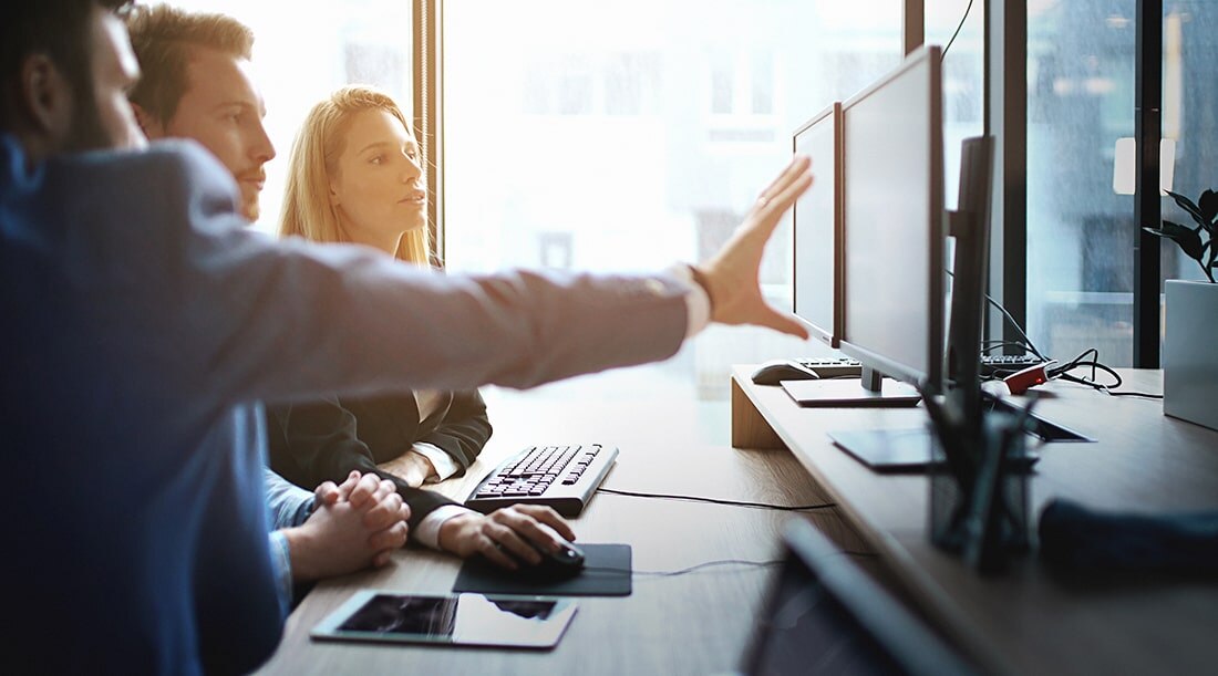 retail professionals meeting around computer dashboards