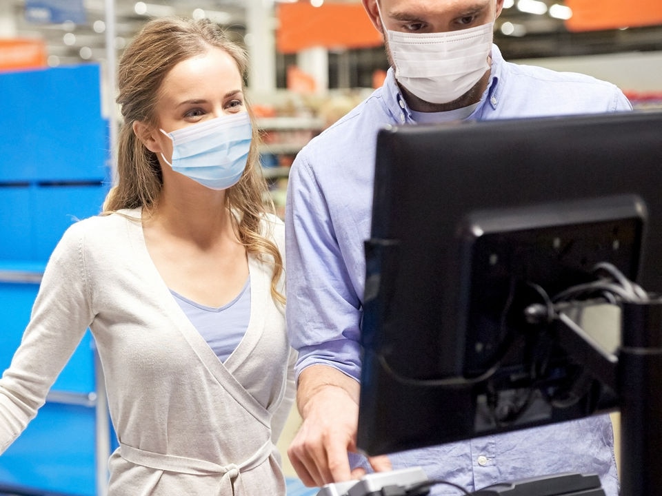 male and female shopper in masks at retail self-checkout pos