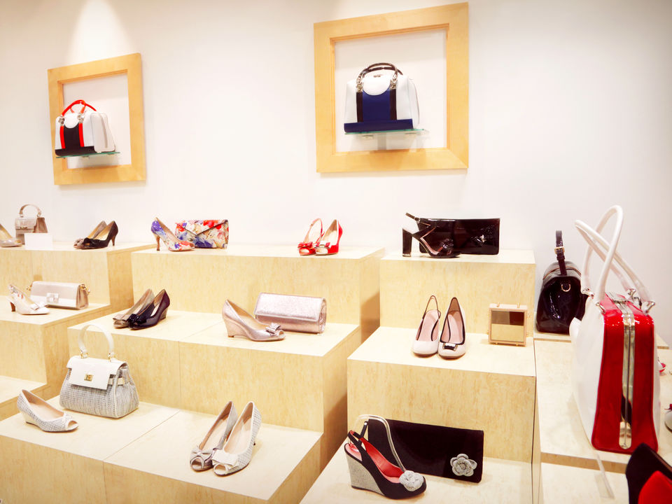 interior of modern handbag and accessories retail store with light wood displays of shoes and pocketbooks