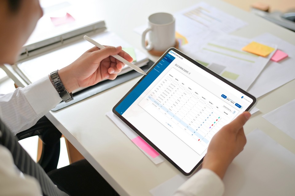 retail manager in brightly lit office working with store data using an electronic stylus on a tablet device