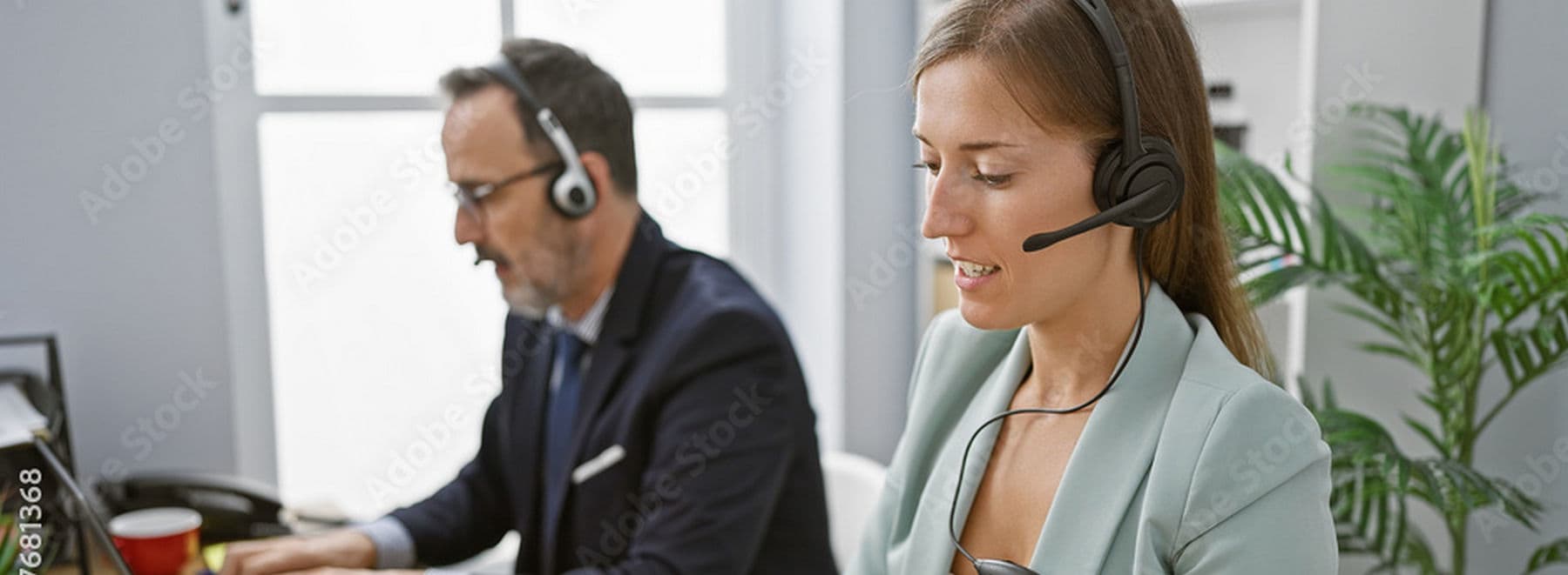 male and female call center reps with headphones sitting in front of monitors assisting customers online