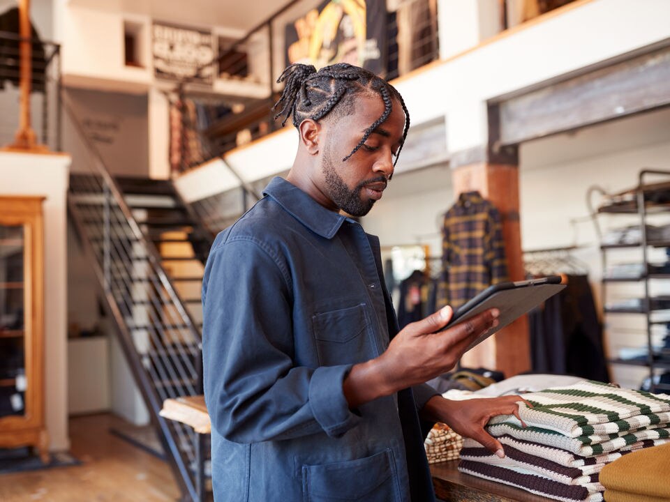 male retail apparel store manager reviewing store information on tablet