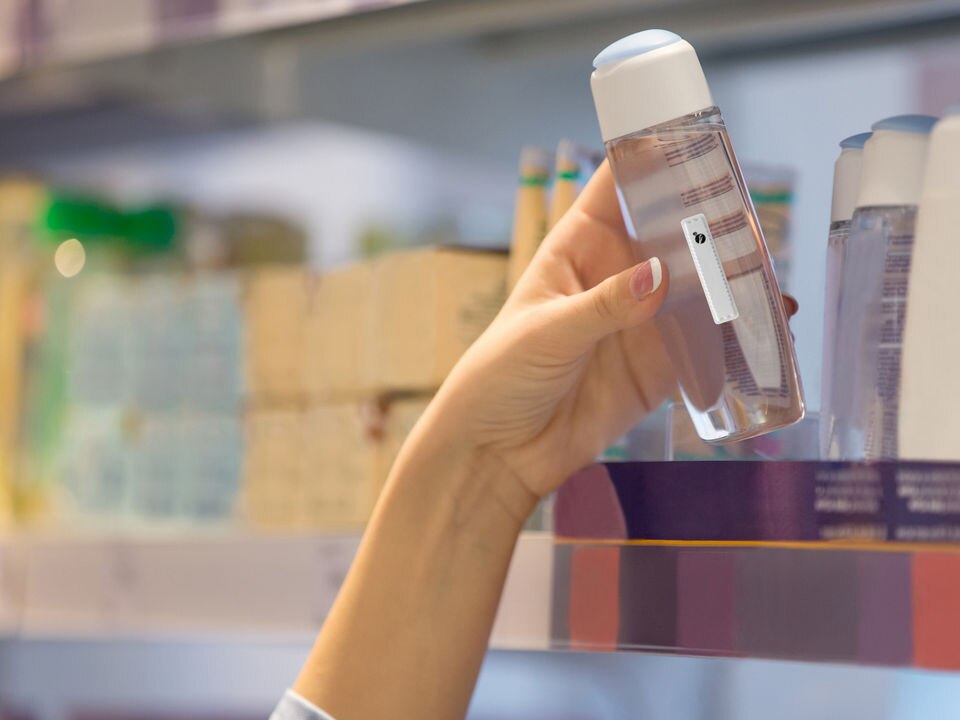 customer hand reaching for item on retail shelf with sensormatic label attached