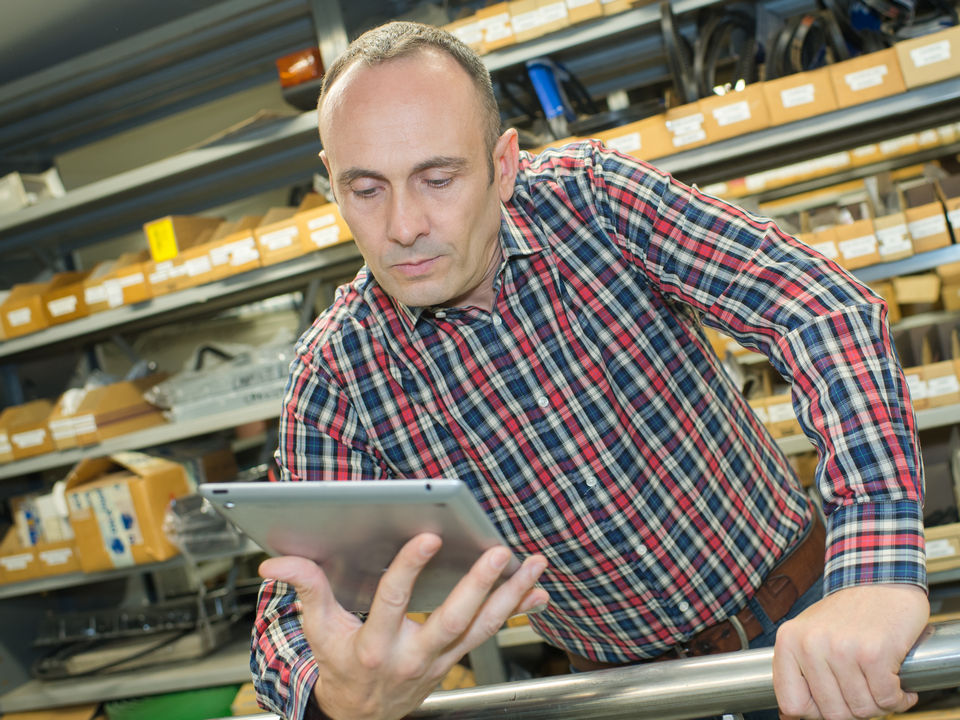 Ein Angestellter im Baumarkt nutzt Bestandsmanagementsoftware auf einem Tablett