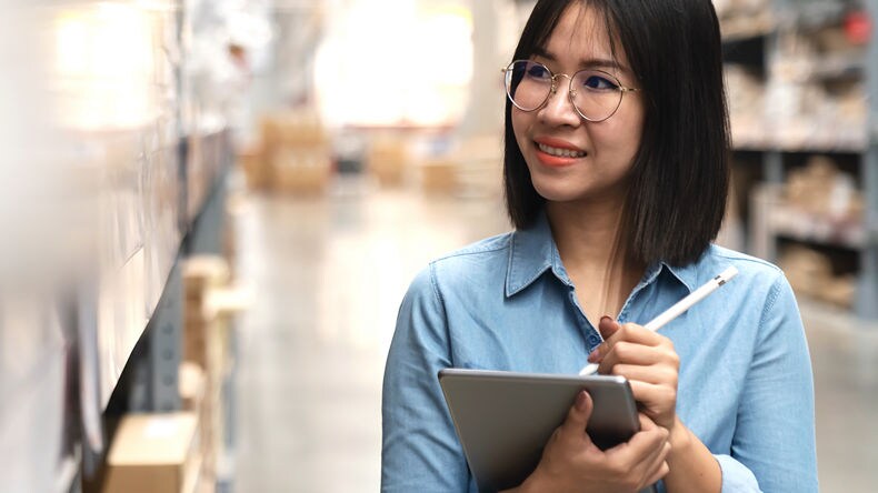 Lagerarbeiterin mit Tablet beim Prüfen von Lagerartikeln