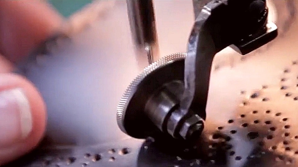 craftsman working on perforating the leather used in johnston and murphy shoes