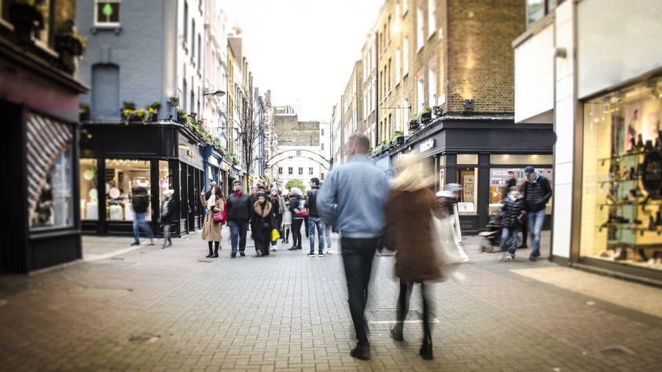 male female couple walking down busy retail shopping street