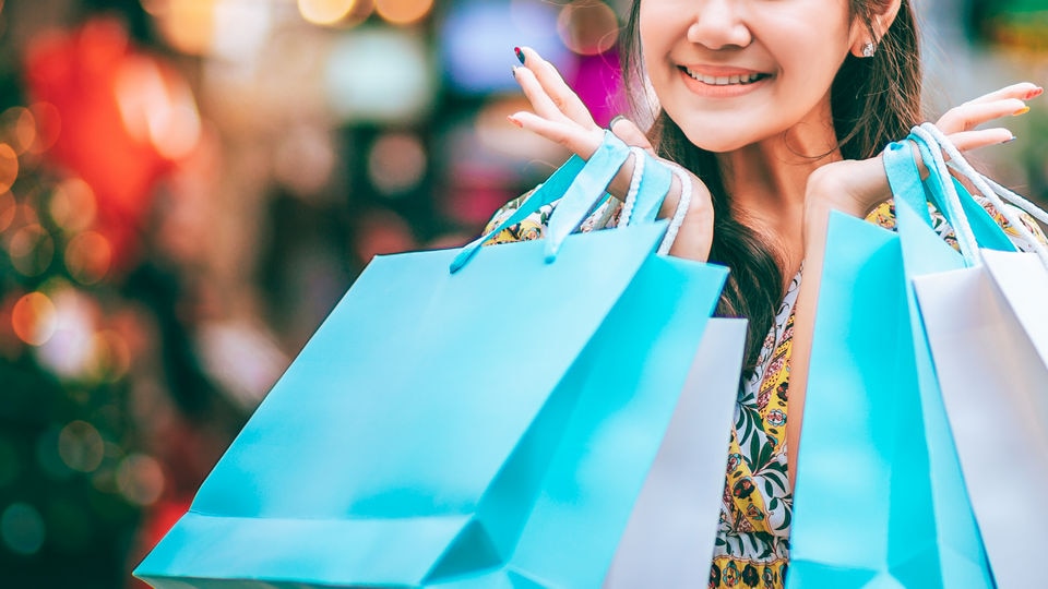 woman with many shopping bags in busy retail shopping area with holiday decorations in background