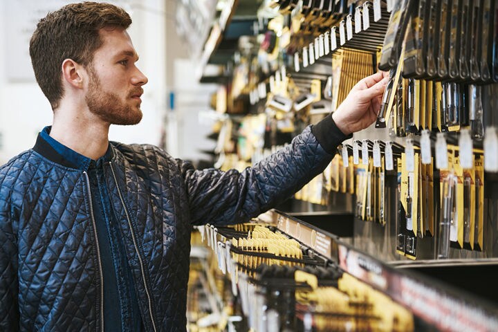 man selecting hardware displayed on retail wall rack