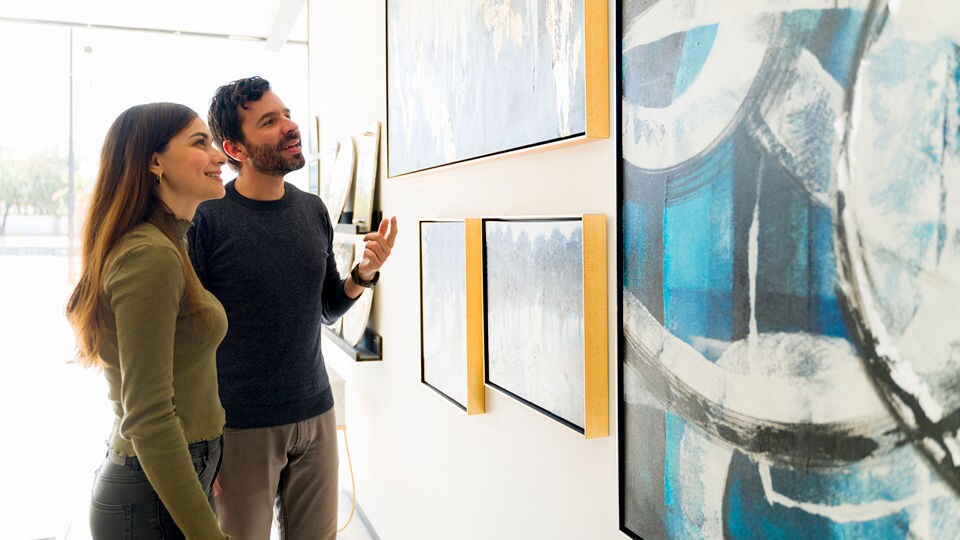 male and female art-lovers looking and talking about paintings on the wall of a gallery or museum