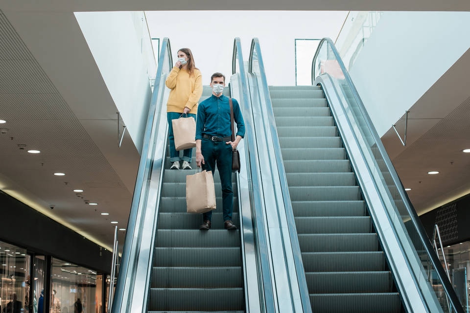 masked shoppers on shopping mall escalator