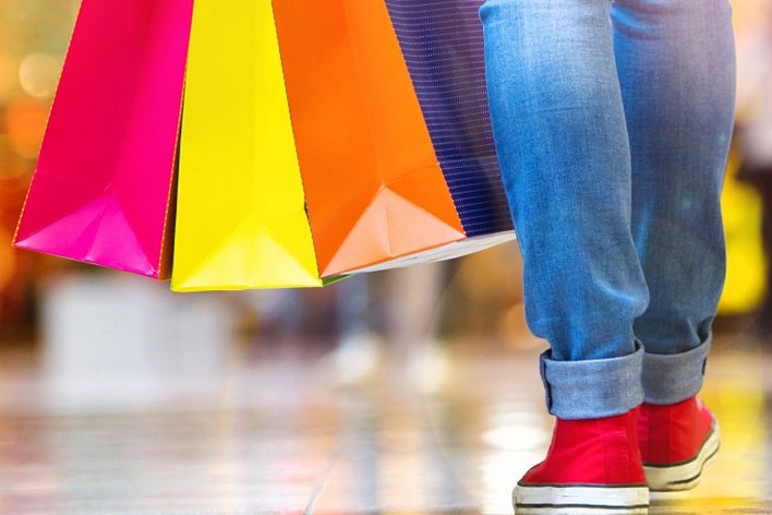 close shot of shopper's legs and bottoms of shopping bags they are carrying