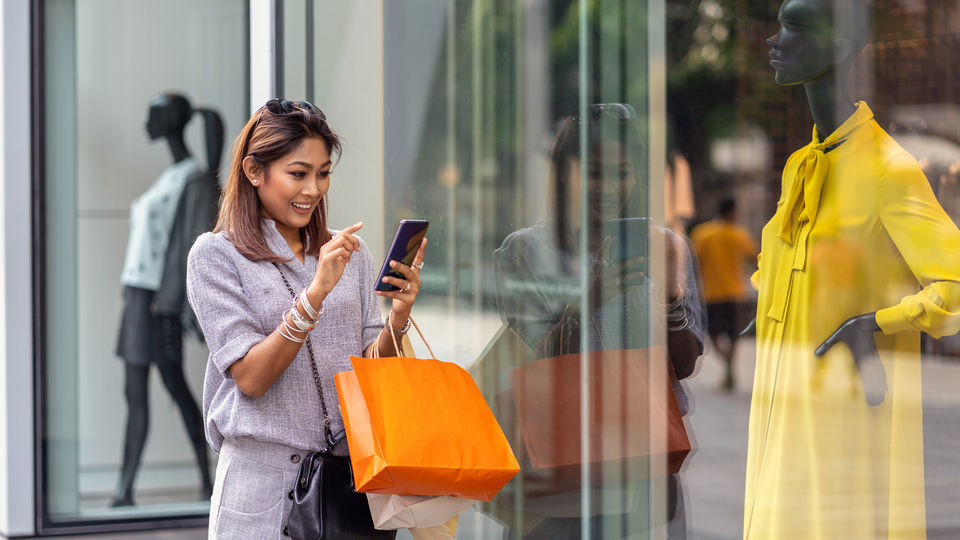 female shopper reviewing her phone outside a retail apparel store