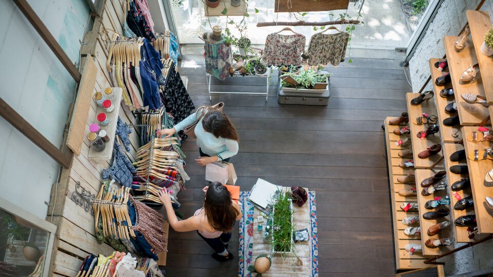 overhead view of two female shoppers in small retail apparel store