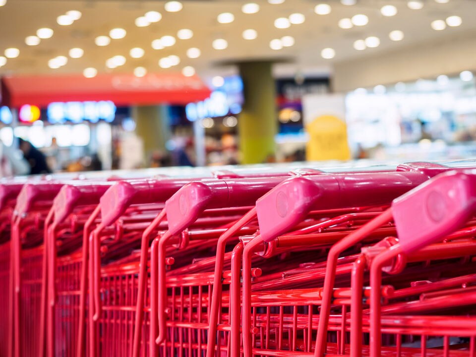 entrance of shopping mall department store with lined up red shopping carts in front