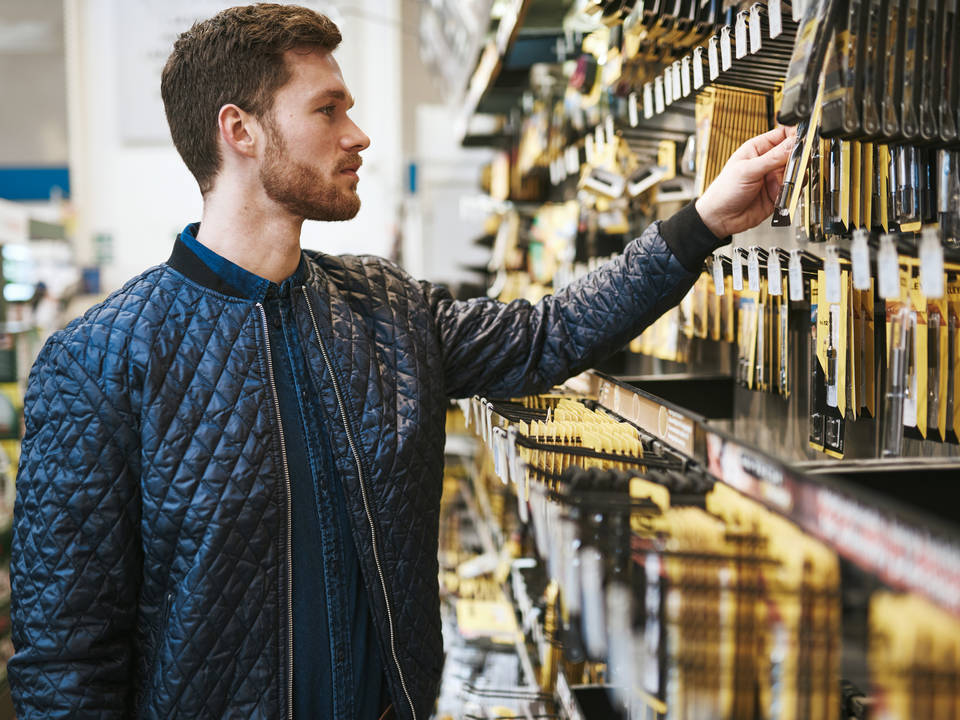 male shopper looking over display of tools in retail hardware diy store
