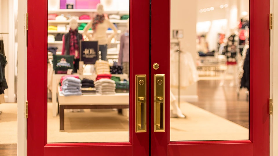 view through red painted double doors into the interior of a retail apparel store