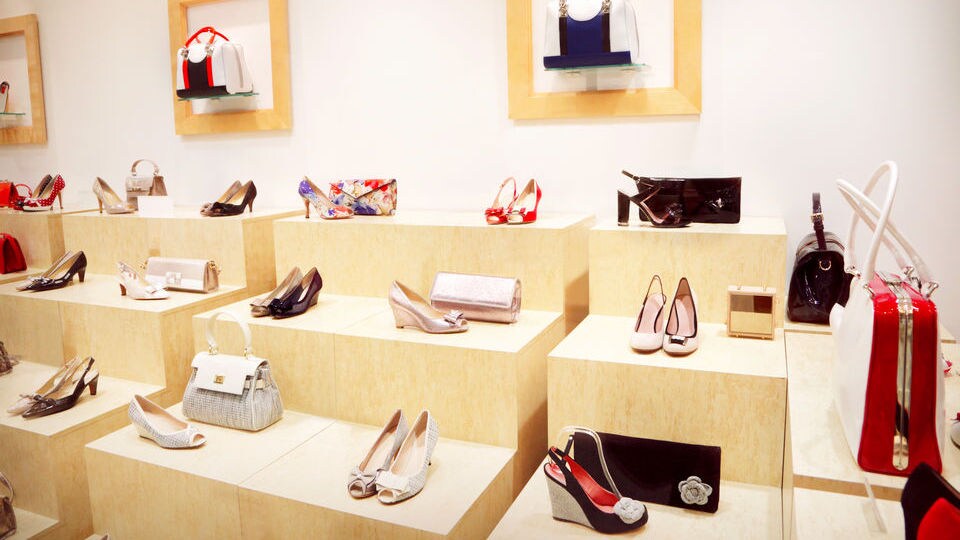 interior of modern handbag and accessories retail store with light wood displays of shoes and pocketbooks