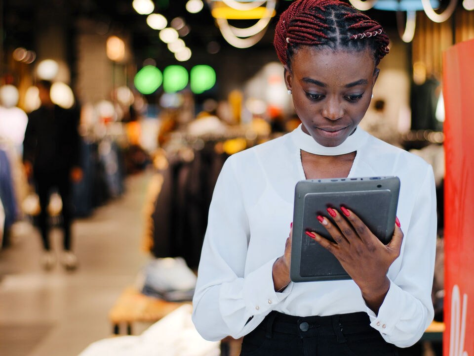 woman store manager reviewing store data on electronic tablet advice at front entrance of apparel store