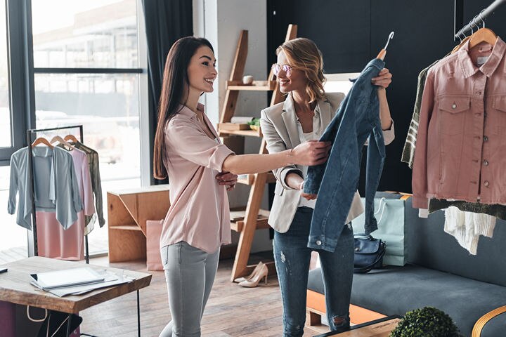 two women looking at item of clothing in retail store