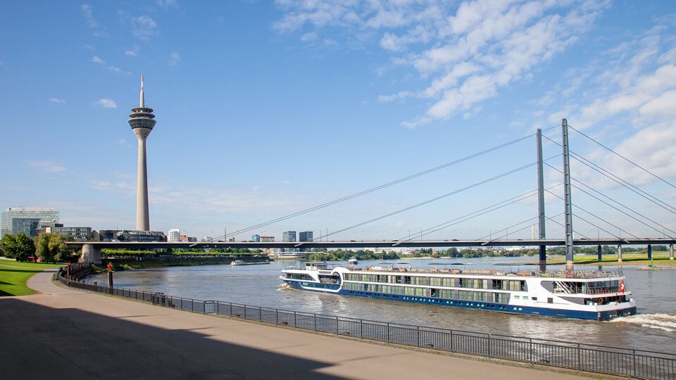 flat top cruising ship in dusselldorf harbor with tower and bridge